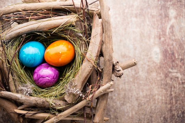 Easter eggs in the nest on rustic wooden background