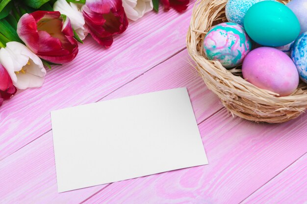 Easter eggs in a nest and tulips on wooden planks