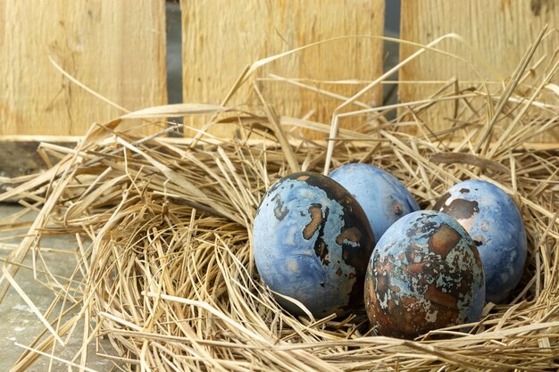 Easter eggs in a nest on a wooden table.