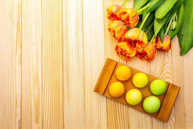 Easter eggs and orange tulip flowers on a wooden table