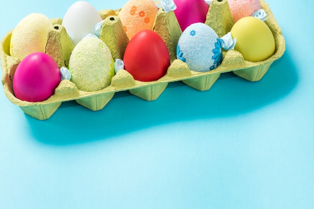 Easter eggs painted in bright colors in a carton box