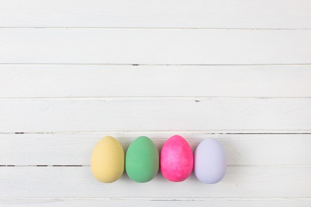 Easter eggs painted in pastel colors on a white wood background