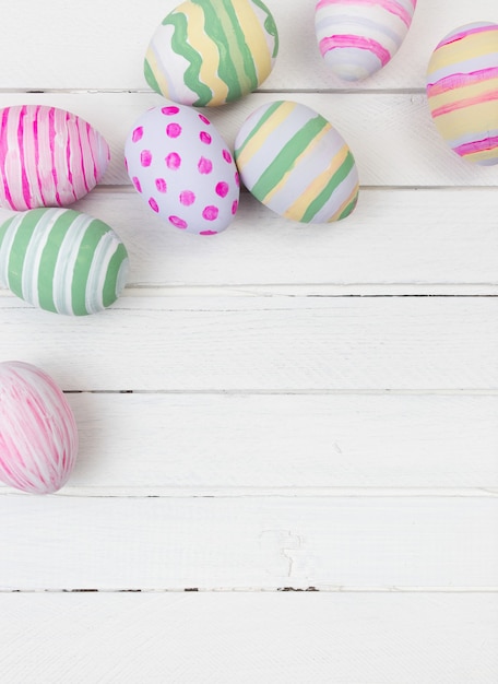 Easter eggs painted in pastel colors on a white wood background