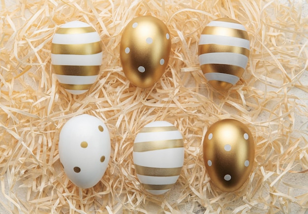 Easter eggs painted with gold paint on a straw background