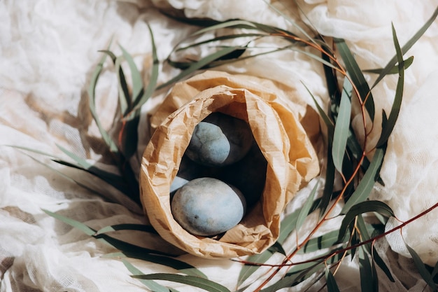 Easter eggs pastel colored in a small wicker basket on light background Minimal Easter celebration concept dyed chicken eggs