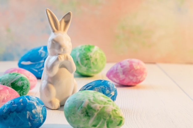 파스텔 색상의 부활절 달걀과 밝은 배경에 있는 토끼와 텍스트 휴일 엽서 포스터