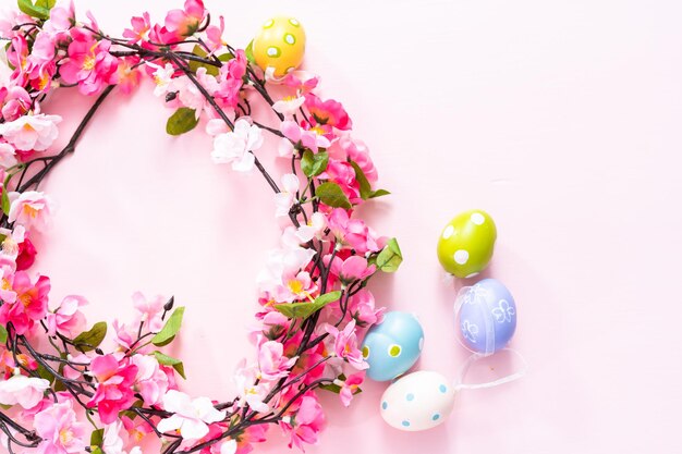 Easter eggs and pink flowers on a pink backgorund.