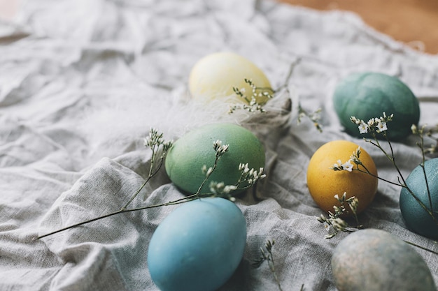 Easter eggs on rustic napkin with flowers stylish natural dyed\
egg spring flowers feathers