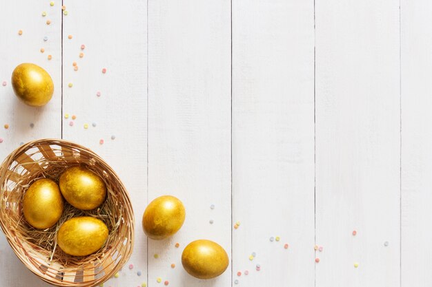 Easter eggs in small basket on wooden background