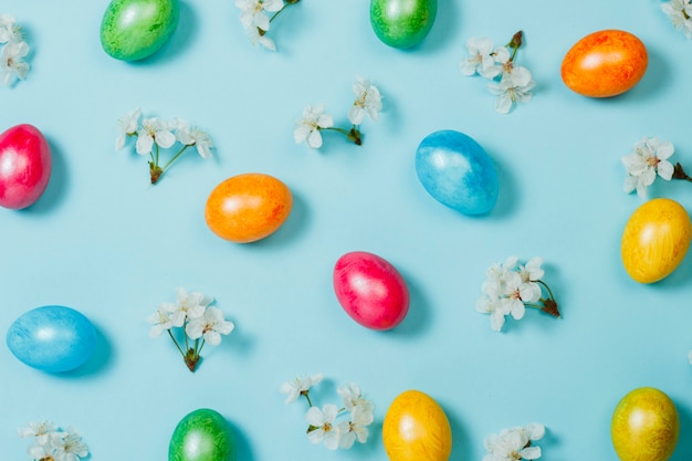 Easter eggs and spring flowers on a blue background. Concept of celebrating Easter. Flat lay, top view