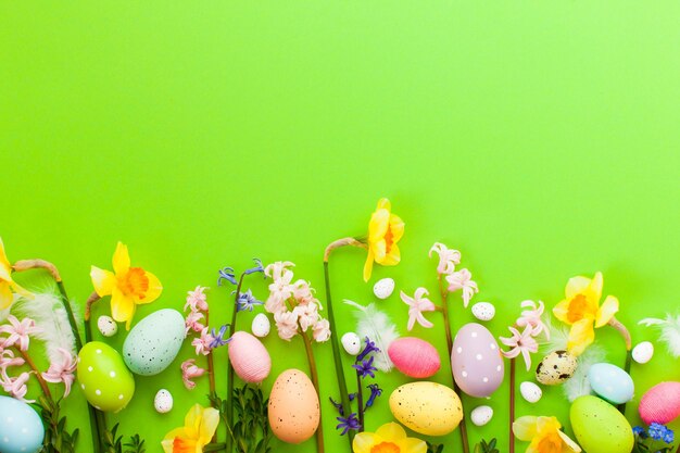 Easter eggs and spring flowers on the green background. Top view Easter background with copy space