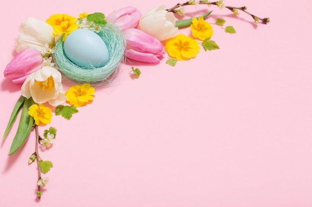 Easter eggs and spring flowers on pink background