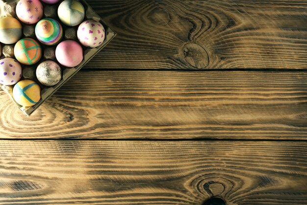 Uova di pasqua su un supporto su una superficie di legno con posto per il testo, vista dall'alto