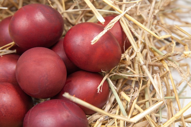 Easter eggs in a straw nest on rustic wooden background. Happy Easter!