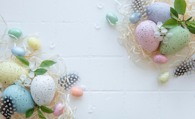 Easter eggs in straw nest on a white tile background