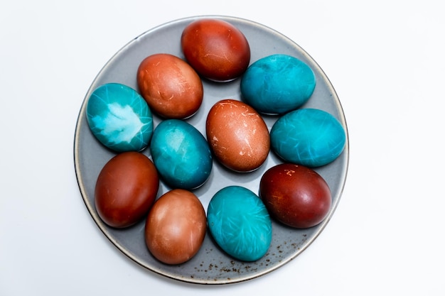Easter eggs Top view of a plate with colored eggs on a white background Orthodox traditions