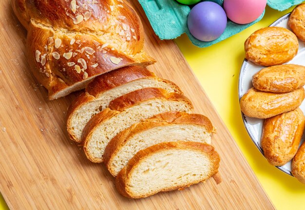 Photo easter eggs and tsoureki braid greek easter sweet bread on yellow color background