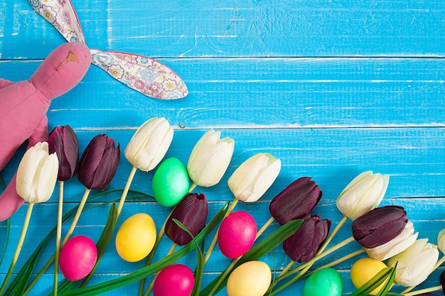 Easter eggs and tulips on blue wooden planks