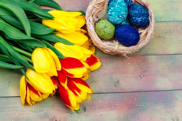 Easter eggs and tulips on wooden planks