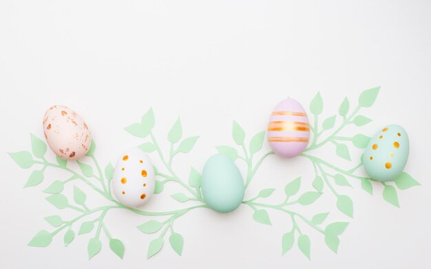 easter eggs on white background with paper leaves