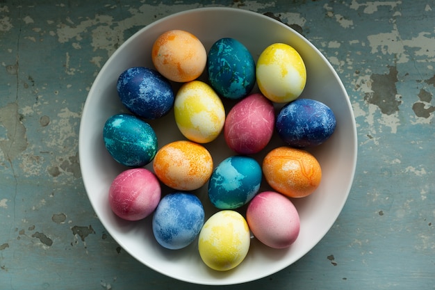 Easter eggs in white dish on light blue old concrete background