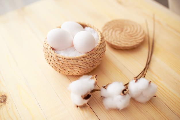 Easter eggs on white wooden table. Flowers and candies around.