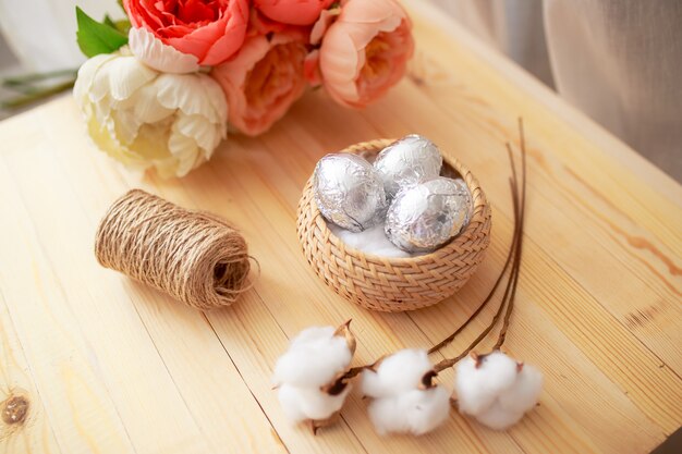 Easter eggs on white wooden table. Flowers and candies around.