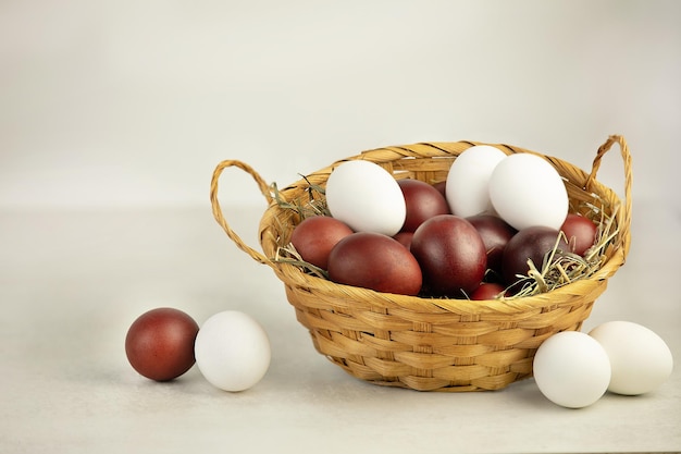 Easter eggs in a wicker basket on white background with eggs near by