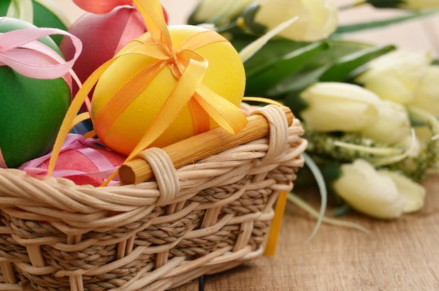 Easter eggs with bows in the basket over floral background