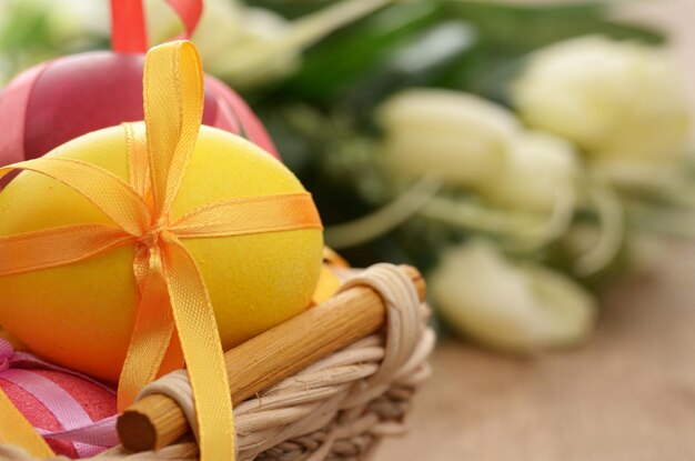 Easter eggs with bows in the basket over floral background