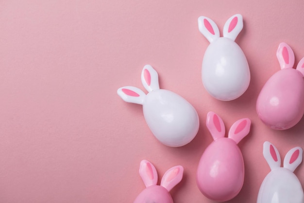 Easter eggs with bunny ears on a pastel pink background