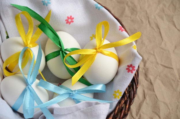 カラフルなサテンのリボンの弓とイースターエッグ春の休日イースターホリデーの卵のバスケット