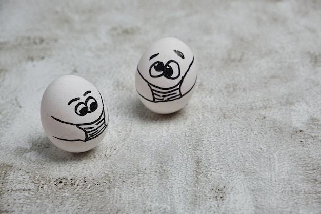 Easter eggs with COVID 19 protection concepts. DIY easter eggs with painted funny faces wearing mask for Easter holidays decoration. Selective focus with copy space.