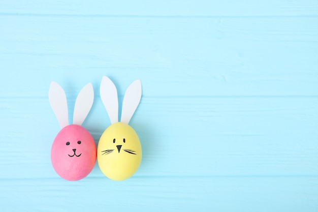 Photo easter eggs with cute faces and ears on a colored background