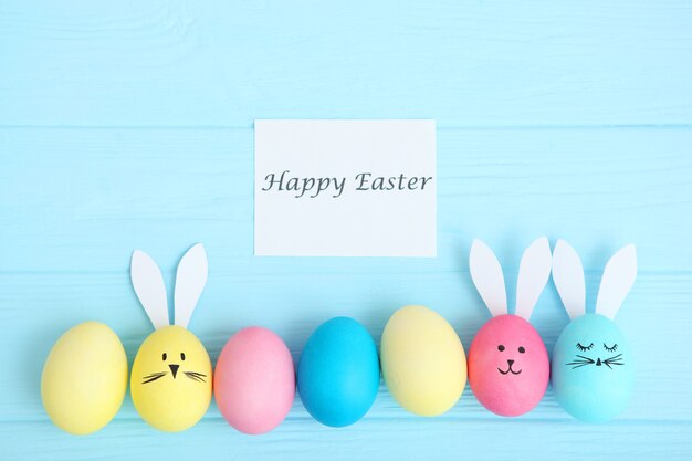 Easter eggs with cute faces and ears on a colored background