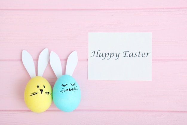 Easter eggs with cute faces and ears on a colored background