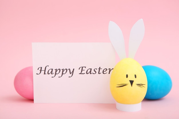 Easter eggs with cute faces and ears on a colored background