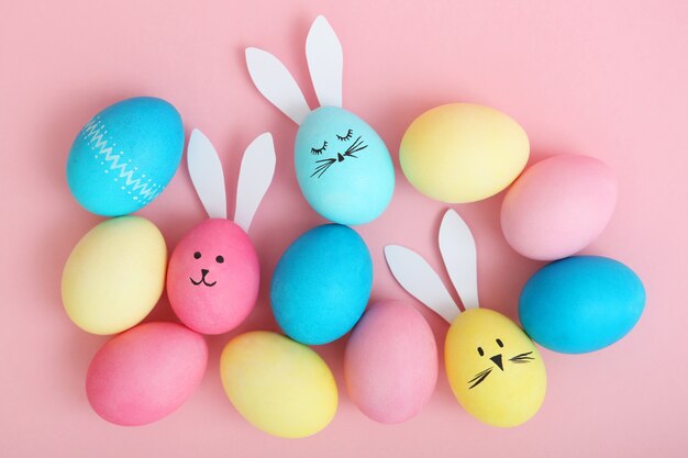 Easter eggs with cute faces and ears on a colored background