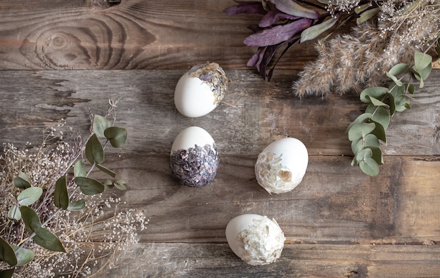 Uova di pasqua con fiori secchi su un tavolo di legno. felice pasqua concetto.