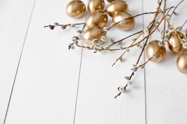 Easter eggs with pussy willow branches on white wooden table happy holiday background