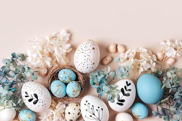 Foto uova di pasqua con dolci e fiori su beige buon concetto di pasqua uova bianche e blu e nido carino con caramelle