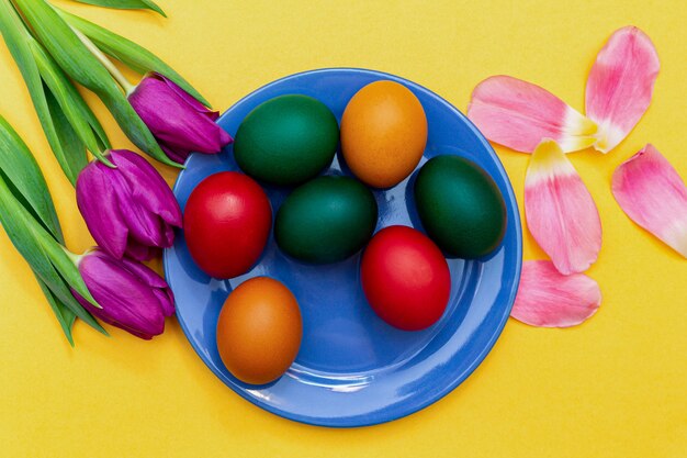 Easter eggs with tulips on a blue dish on a yellow