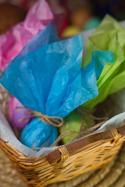 Easter eggs wrapped in colored paper inside a wicker basket