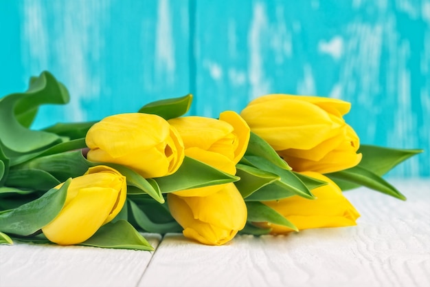 Easter eggs and yellow tulips on white wooden table