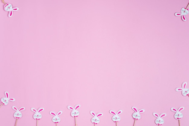 Photo easter festive backdrop with small handmade decorative paper bunnies on a pastel pink background.