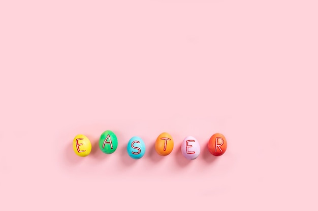 Фото Пасхальная плоская композиция с красочными нарисованными естественными яйцами на розовом фоне