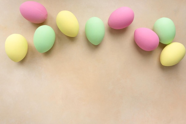 Easter flat lay. Eggs painted in pastel colors on beige background, space for text