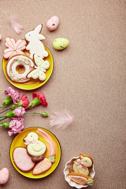 Easter flat lay with copy space Decorated Easter cookies pink flowers with feathers Spring pastel background