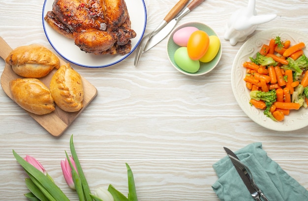 Easter food on white rustic table pastel colored eggs roasted chicken vegetables