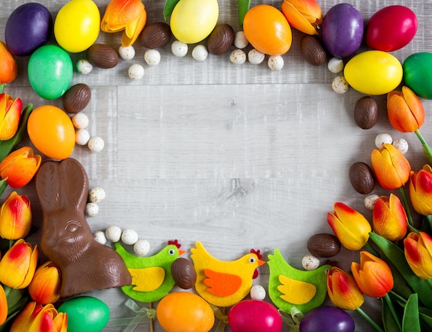 다채로운 계란 장식 병아리 튤립 초콜릿 토끼와 과자의 부활절 프레임 배경 닫습니다